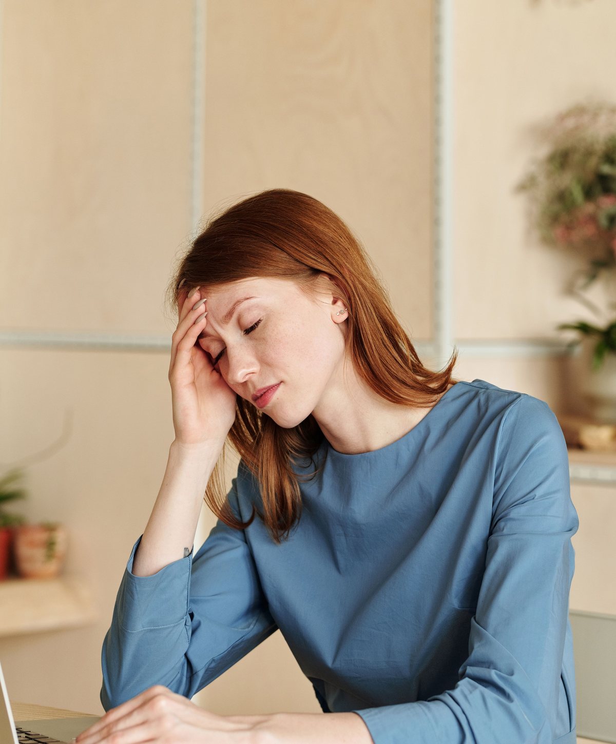Une femme fatiguée devant son ordinateur, la main sur le front